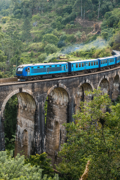 Blue train rounds bend over stone bridge