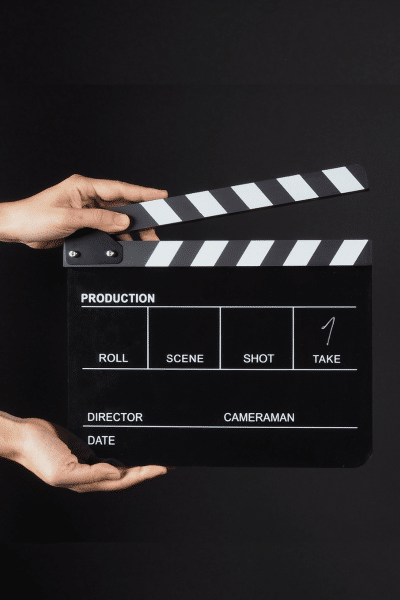 Hands hold a scene clapperboard on a dark set