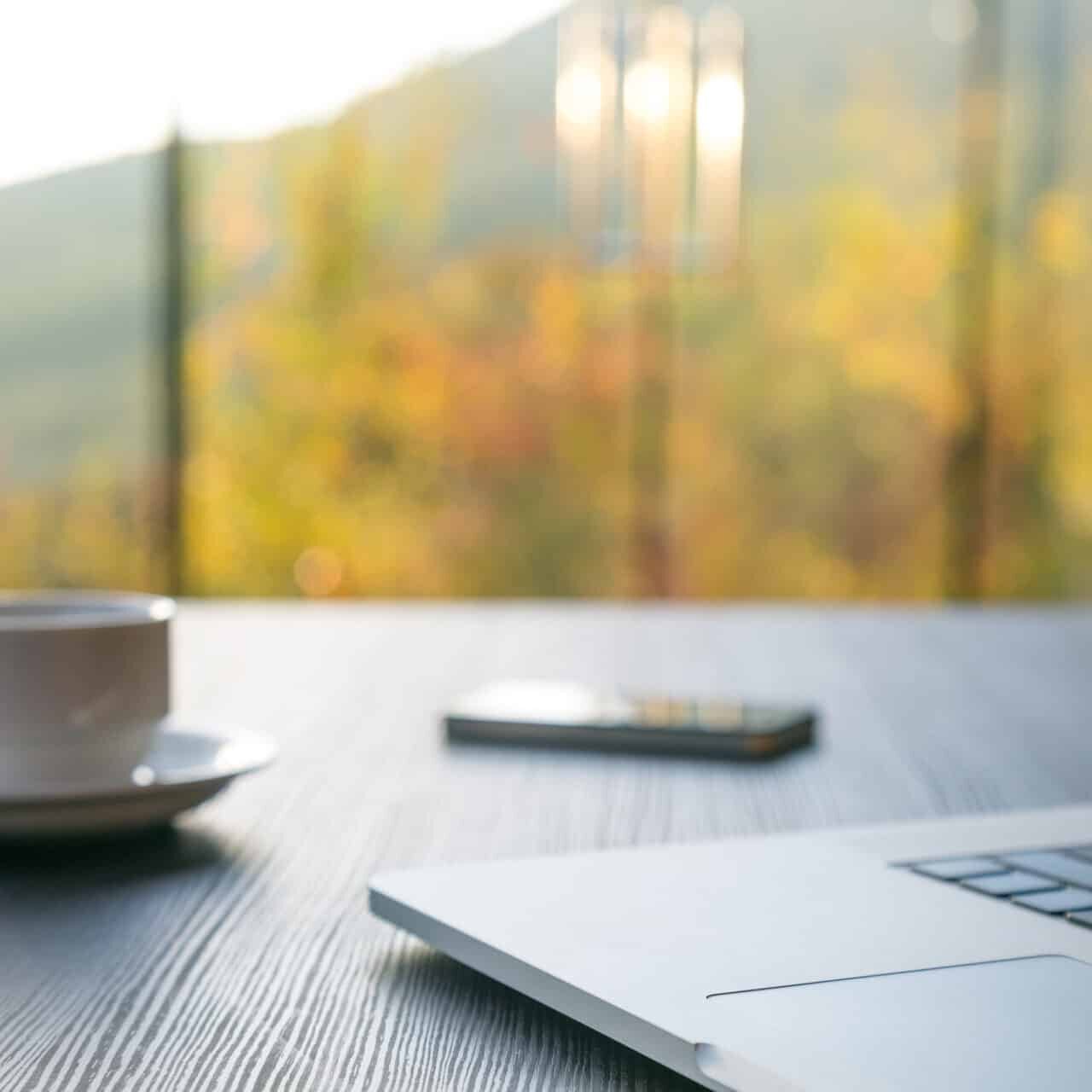 A laptop with a cup of coffee on a wooden table