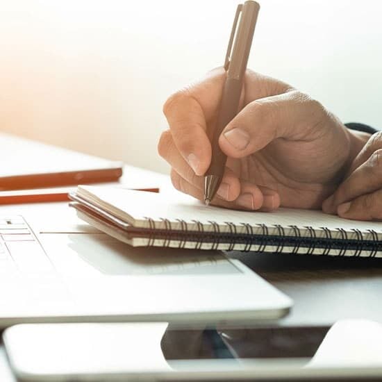 Writing notes in notebook with a pen.